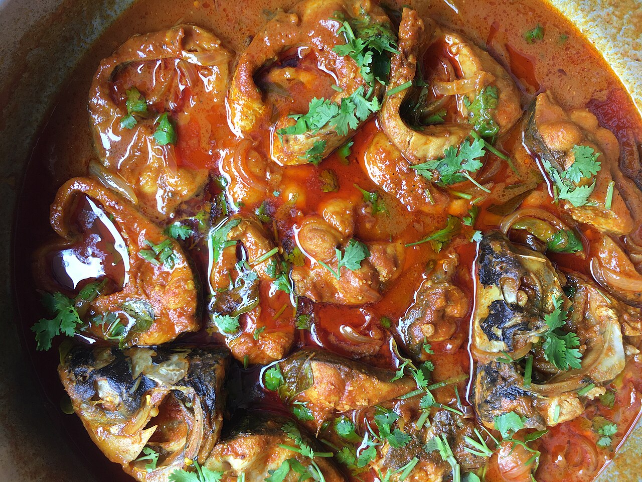 Andhra fish pulusu, fish pieces in a reddish tamarind curry